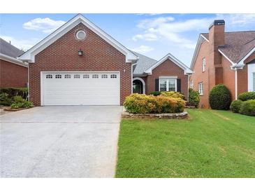 Charming brick home featuring a two-car garage, manicured lawn, and mature landscaping at 2323 Blackberry Ct, Snellville, GA 30078