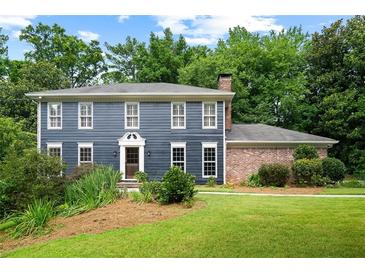 Charming two-story home featuring blue siding, white trim, a manicured lawn, and mature landscaping at 2340 Castleridge Ct, Tucker, GA 30084