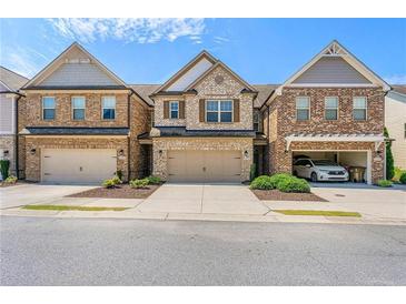 Beautiful brick townhome with two car garage and manicured landscaping at 8295 Village Pl, Suwanee, GA 30024