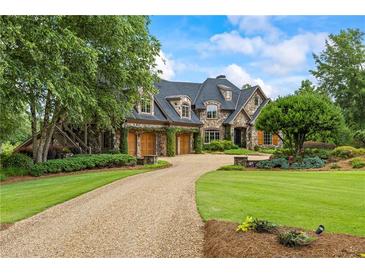 Stunning stone home featuring a curved driveway, three-car garage, and professionally landscaped yard at 4239 Lower Jersey Rd, Covington, GA 30014