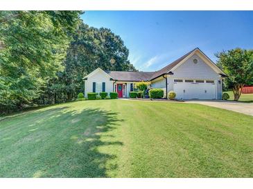 Well-maintained home with a manicured lawn, lush greenery, and a charming red front door at 2321 Sunnyview Ln, Dacula, GA 30019