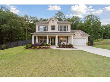 Inviting two-story home with a columned front porch and well-manicured lawn surrounded by mature trees at 404 Arden, Ellenwood, GA 30294