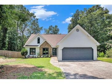 Charming home with a well-maintained lawn, stone accents, a gray two-car garage and lush landscaping at 2085 Castle Royale Dr, Lawrenceville, GA 30043