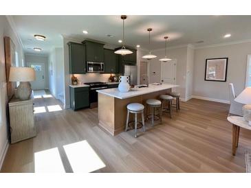 Modern kitchen features an island with seating, stainless steel appliances, and hardwood floors throughout at 229 Dahlia Dr, Woodstock, GA 30188