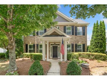 Charming brick home features manicured landscaping, covered entry, and an American flag for a welcoming curb appeal at 214 Harmony Lake Dr, Canton, GA 30115
