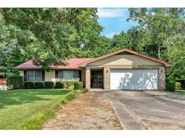 Charming single-story home with mature trees, lush lawn, two-car garage, and a brick and siding exterior at 4866 S Lilburn Stone Mountain Road Sw Rd, Lilburn, GA 30047