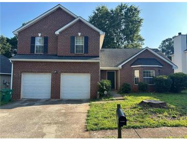 Charming two-story brick home featuring an attached two car garage and a well-maintained front yard at 5942 Idlewood Pl, Lithonia, GA 30038