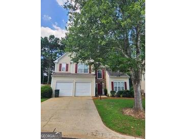 Two-story home featuring a two-car garage and red shutters accenting the beige siding at 1447 Evanston, Marietta, GA 30062
