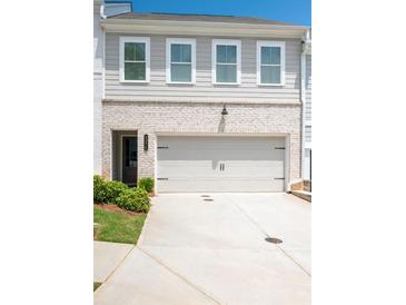 Traditional-style townhome featuring a two-car garage, neutral paint, and a well-maintained lawn at 3374 Verdi Ln, Kennesaw, GA 30144