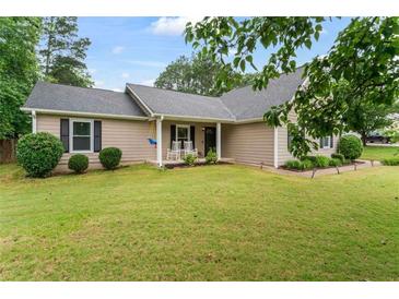 Charming single-story home featuring a manicured lawn and inviting front porch with rocking chairs at 200 Pine Tree Ln, Mcdonough, GA 30252