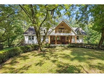 Charming two-story home with a welcoming front porch and lush green lawn surrounded by mature trees at 2121 Jep Wheeler Rd, Woodstock, GA 30188