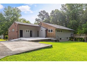 Attractive single-story home featuring gray siding, brick accents, and a large concrete patio in a lush, green yard at 4847 Lakewood Dr, Acworth, GA 30101