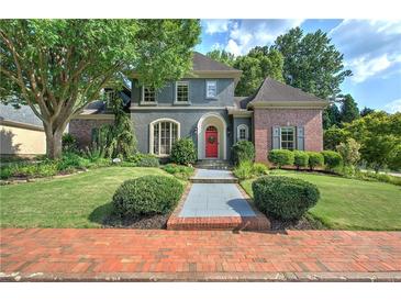 Charming home exterior featuring mature landscaping, inviting entryway, and a red front door at 2160 Kensington Gates Nw Dr, Kennesaw, GA 30152