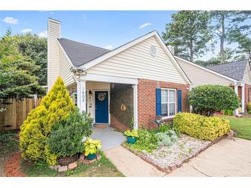 Charming home featuring a blue door and shutters, complemented by beautiful landscaping and mature trees at 1602 Buckingham Place Pl, Woodstock, GA 30188