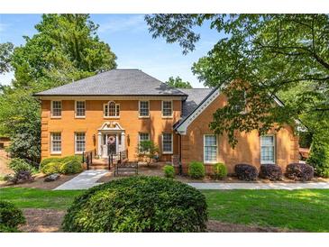 Charming, brick two-story home with mature trees, manicured shrubs, and a manicured lawn at 7575 Hunters Woods W Dr, Atlanta, GA 30350