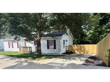 Charming single-story home with a well-manicured lawn and red shutters, shaded by a mature tree and a fenced-in backyard at 1090 Coleman Sw St, Atlanta, GA 30310