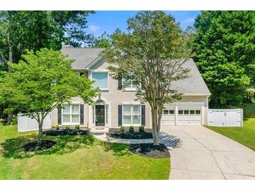 Charming two-story home with a well-manicured lawn, lush trees, a paved driveway, and an attached garage at 1095 Northpoint Trce, Roswell, GA 30076