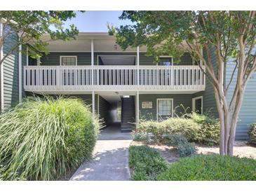 Inviting two-story condo featuring green siding, white railings, and a beautifully landscaped walkway leading to the entrance at 4604 Vinings Central Se Run # 131, Atlanta, GA 30339