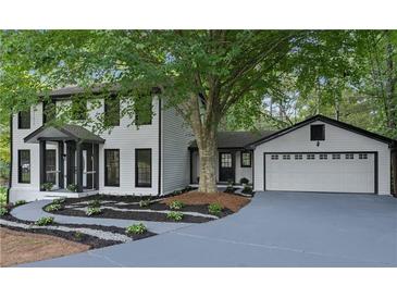 Charming two-story home with white siding, black trim, manicured landscaping, and attached two-car garage at 772 Brookwood Sw Ter, Lilburn, GA 30047