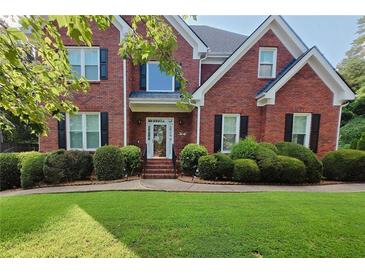 Charming two-story brick home with well-manicured lawn and lush, rounded shrubbery enhancing its curb appeal at 1205 Runnelwood Trail, Snellville, GA 30078