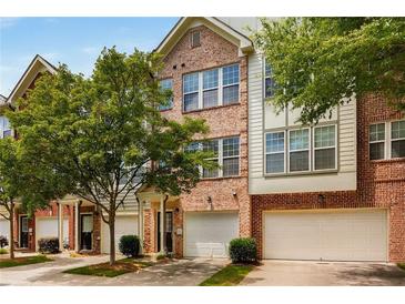 Charming brick townhome exterior featuring an attached garage and lush green trees at 1403 Ashford Creek Ne Cir, Atlanta, GA 30319
