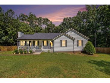Charming single-story home featuring a cozy front porch, green lawn and landscaped garden at 136 Fairlane Dr, Covington, GA 30016