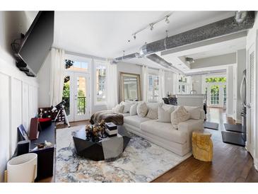 Bright, open living room with hardwood floors and exposed ductwork, filled with natural light from the french doors at 1029 Piedmont Ne Ave # 202, Atlanta, GA 30309