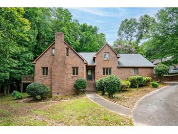 Charming brick home featuring mature trees, a walkway, and a covered entrance, offering a blend of classic and modern design at 9055 Green Valley Ct, Douglasville, GA 30134