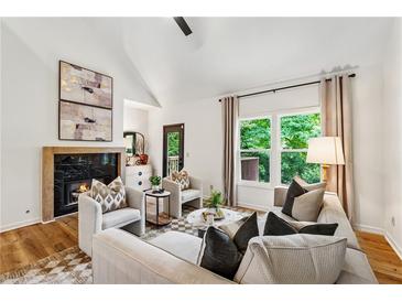Bright living room features a fireplace, vaulted ceiling, and large windows with backyard views at 904 Ivy Green Se Ln, Marietta, GA 30067
