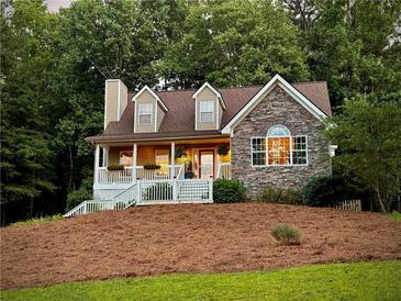 Charming home with stone facade, dormer windows, and a cozy front porch nestled among mature trees at 9176 Lakeview Pkwy, Villa Rica, GA 30180