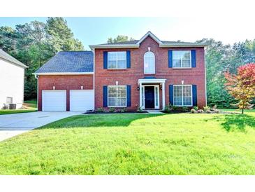 Inviting two-story brick home featuring a well-manicured lawn, two-car garage, and classic dark blue shutters at 2035 Lena Carter Rd, Buford, GA 30519
