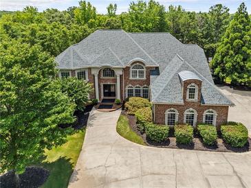 Stately brick home featuring manicured landscaping and mature trees providing shade and privacy at 55 Moray Pl, Covington, GA 30014