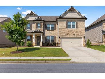Charming two-story home with a well-manicured lawn, stone accents, and an attached two-car garage at 3717 Blue Goose Ln, Loganville, GA 30052