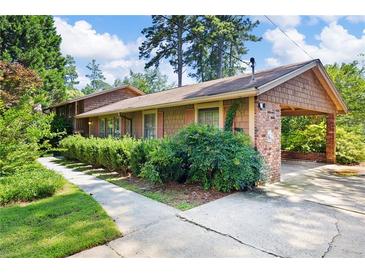 Charming home exterior with brick carport, cedar shake siding and manicured front landscape at 255 Jade Cove Dr, Roswell, GA 30075