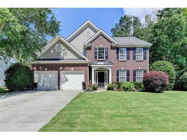Charming two-story brick home with a well-manicured lawn, two-car garage, and beautifully landscaped front yard at 127 Bradshaw Park Dr, Woodstock, GA 30188