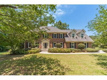 Charming two-story brick home with mature trees and manicured landscaping at 4989 Woodfall Sw Dr, Lilburn, GA 30047