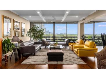 Bright living room featuring hardwood floors, multiple seating areas, and expansive windows with city views at 2660 Peachtree Nw Rd # 13F, Atlanta, GA 30305