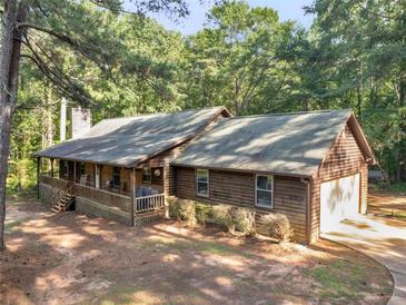 Beautiful single-story wood home featuring a charming front porch and attached garage nestled in a wooded lot at 1000 Coan Dr, Locust Grove, GA 30248