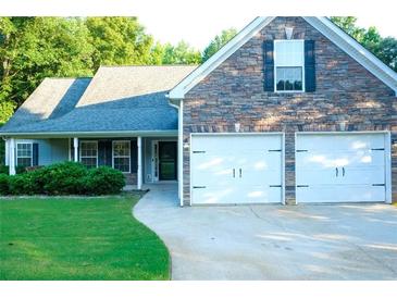 Charming home featuring a stone facade, two-car garage, well-maintained lawn, and covered front porch at 85 Lamar Ln, Covington, GA 30016