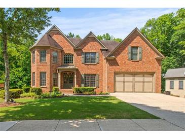 Elegant brick home with a well-manicured lawn, lush greenery, and attached two-car garage at 1170 Shellnut Trl, Hoschton, GA 30548