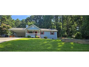 Charming, light blue single-Gathering home with a well-manicured front yard and covered parking area at 2357 Whitehouse Rd, Dacula, GA 30019