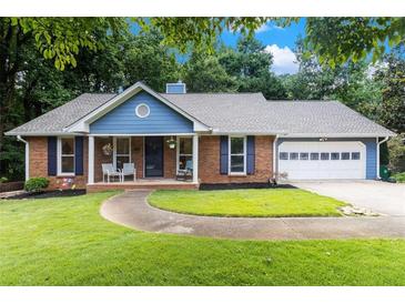 Charming brick home with a well-manicured lawn, inviting front porch, and attached two-car garage at 1402 Mclendon Dr, Decatur, GA 30033