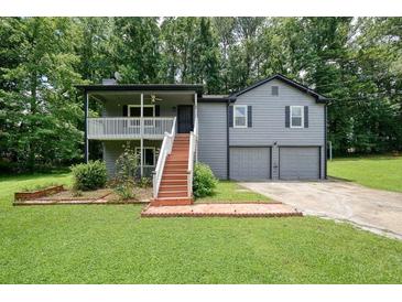 Charming two-story home with gray siding, a front porch, and a two-car garage nestled among lush trees at 174 Village Dr, Hiram, GA 30141