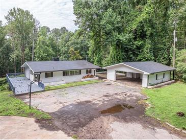 Charming single-story home with a spacious deck and covered carport, surrounded by lush greenery at 8035 Rockbridge Rd, Lithonia, GA 30058
