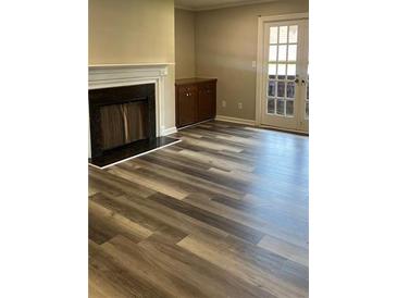 Bright living room with a cozy fireplace and newly installed hardwood flooring at 188 Rue Fontaine, Lithonia, GA 30038