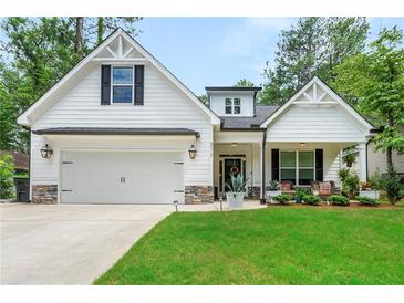 Charming home featuring a well-maintained lawn, stone accents, and an inviting covered front porch at 5015 Monticello Dr, Villa Rica, GA 30180