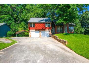 Charming home boasts a stone facade, two-car garage, and a well-maintained front yard, all nestled on a tree-lined lot at 1030 Chapman Ln, Stone Mountain, GA 30088