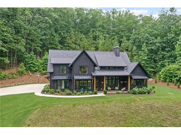 Stunning dark modern farmhouse with inviting front porch and lush lawn with a beautiful wooded backdrop at 2100 Mountain Cove Ct, Woodstock, GA 30188