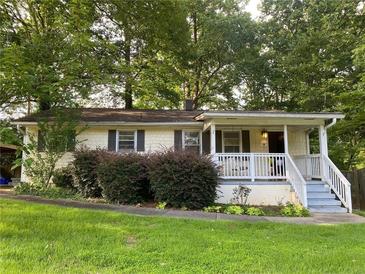 Charming single-story home featuring a cozy front porch and mature trees in a serene, landscaped yard at 1003 Valley Se Dr, Smyrna, GA 30080