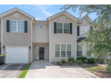 Attractive townhome featuring light siding, black shutters, and a one-car garage on a sunny day at 2284 Nicole Dr, Hampton, GA 30228
